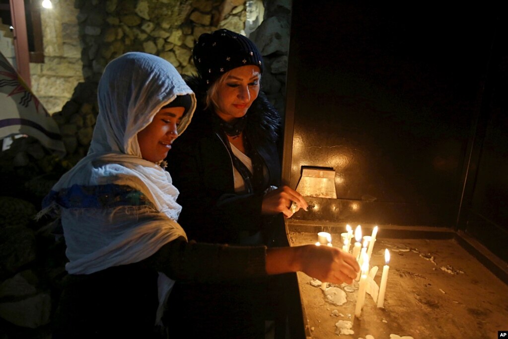 Iraqi Christians light candles after a Christmas Eve Mass in St. Joseph's Church in Baghdad, Dec. 24, 2017.