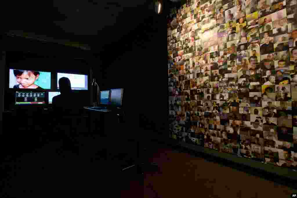 A wall is plastered with pictures of men suspected of soliciting an underage girl for webcam sex while a Terre des Hommes researcher, center rear, takes the identity of fake 10-year-old Sweetie from the Philippines, top left, in a computer-generated image, during a media opportunity in Amsterdam, Netherlands.