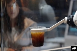 In this May 22, 2019, photo, a customer waits for a coffee in front of a robot named b;eat after placing an order at a cafe in Seoul, South Korea. (AP Photo/Lee Jin-man)