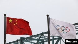 中國國旗和奧運旗幟在北京冬奧組委會外飄揚。 （2021年3月30日）