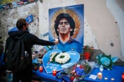 Seorang pria memegang lilin untuk menghormati meninggalnya legenda sepak bola Diego Maradona, di "Quartieri Spagnoli", Naples, Kamis, 26 November 2020.