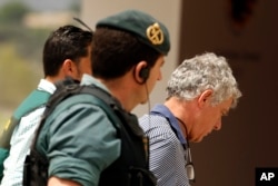 Former President of the Spanish Football Federation Angel Maria Villar, right, is lead by Spanish Civil Guard policeman to enter the Federation headquarters during an anti-corruption operation in Las Rozas, outside Madrid, July 18, 2017.