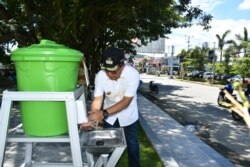 Bupati Poso Darmin Agustinus Sigilipu memeriksa salah satu fasilitas tong air yang didirikan di taman terbuka hijau kota poso untuk memudahkan masyarakat mencuci tangan. (Foto: Humas Pemkab Poso)