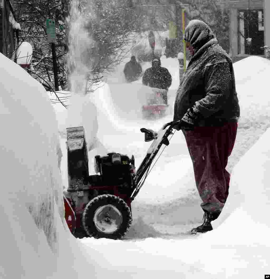 Un homme enlève la neige sur une rue à Concrd, NH, dimanche 15 février 2015.