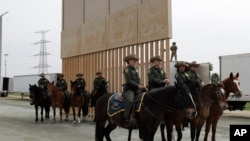 FILE - U.S. Border Patrol officers on horseback watch President Donald Trump (not pictured) review border wall prototypes in San Diego, March 13, 2018.