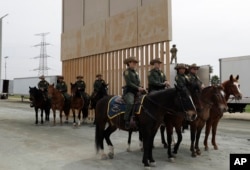 U.S. Border Patrol officers on horseback watch President Donald Trump review border wall prototypes, March 13, 2018, in San Diego.
