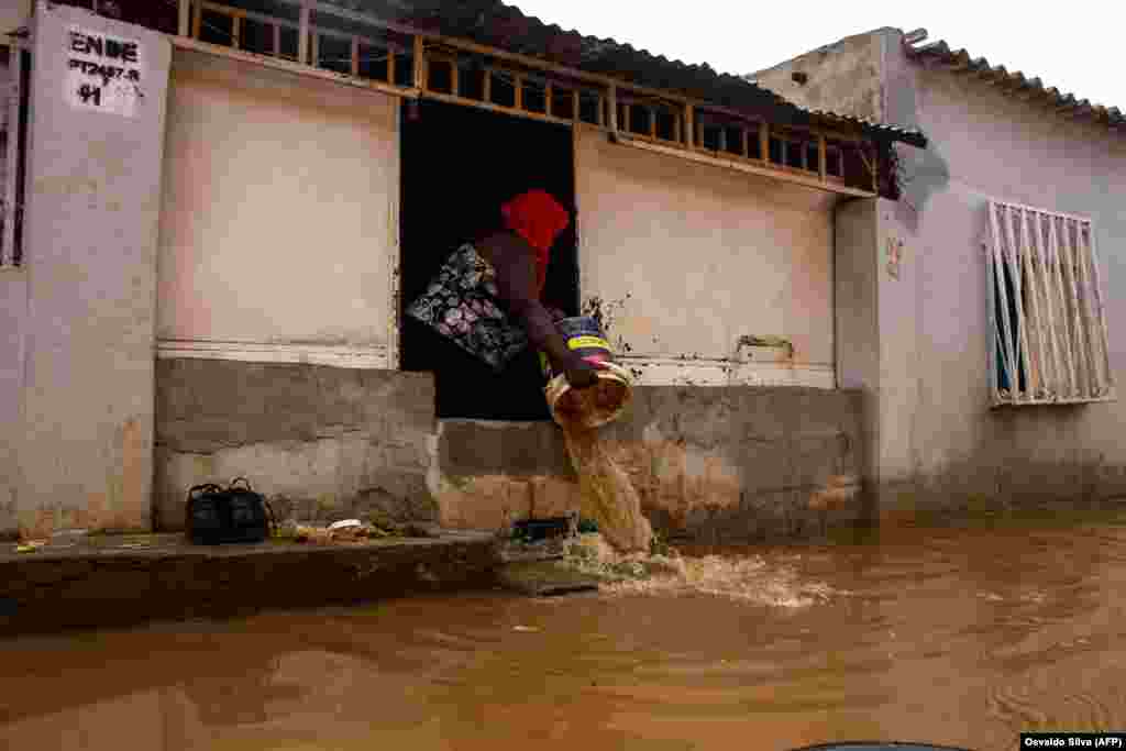 Uma moradora atira &#225;gua de dentro da sua casa inundada no Futungo, Luanda - Angola, a 20 de Abril, um dia depois de fortes chuvas terem causado a morte a 14 pessoas