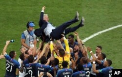 Para pemain tim nasional Prancis melempar pelatih Didier Deschamps ke udara saat melakukan selebrasi usai pertandingan final antara Prancis dan Kroasia di Piala Dunia Sepak Bola 2018 di Stadion Luzhniki, Moskow, Rusia, Minggu, 15 Juli 2018. (Foto: AP)