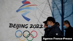 لوگ بیجنگ سرمائی اولمپکس کا ایک بینر دیکھ رہے ہیں۔ یکم دسمبر 2021ء 