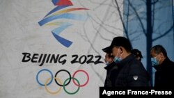 People walk past the Beijing 2022 Winter Olympics logo at the Shougang Park in Beijing on Dec. 1, 2021. 