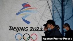 People walk past the Beijing 2022 Winter Olympics logo at the Shougang Park in Beijing on Dec. 1, 2021. 