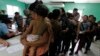 Des femmes et leurs enfants, dont beaucoup espéraient atteindre les États-Unis, font la queue pour s'inscrire au Centre hondurien pour les migrants de retour après avoir été expulsés du Mexique, à San Pedro Sula, dans le nord du Honduras, le 20 juin 2014. REUTERS/Jorge Cabrera