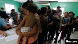 Des femmes et leurs enfants, dont beaucoup espéraient atteindre les États-Unis, font la queue pour s'inscrire au Centre hondurien pour les migrants de retour après avoir été expulsés du Mexique, à San Pedro Sula, dans le nord du Honduras, le 20 juin 2014. REUTERS/Jorge Cabrera