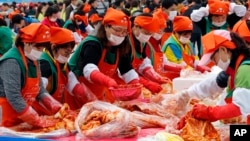 South Koreans and tourists make kimchi to donate to needy neighbors during the Seoul kimchi festival in Seoul, South Korea, Friday, Nov. 6, 2015.