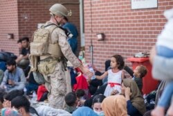 Pasukan Marinir AS memberikan air bersih untuk seorang anak selama evakuasi. (Foto: US Marine Corp via AP)