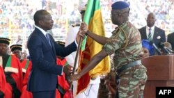 Patrice Talon (L) is handed a national flag during his swearing in as president of Benin at Charles de Gaulle Stadium in the capital Porto-Novo, April 6, 2016.