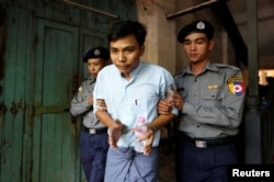 Detained Reuters journalist Kyaw Soe Oo is escorted by police before a court hearing in Yangon, Myanmar, Apr. 11, 2018