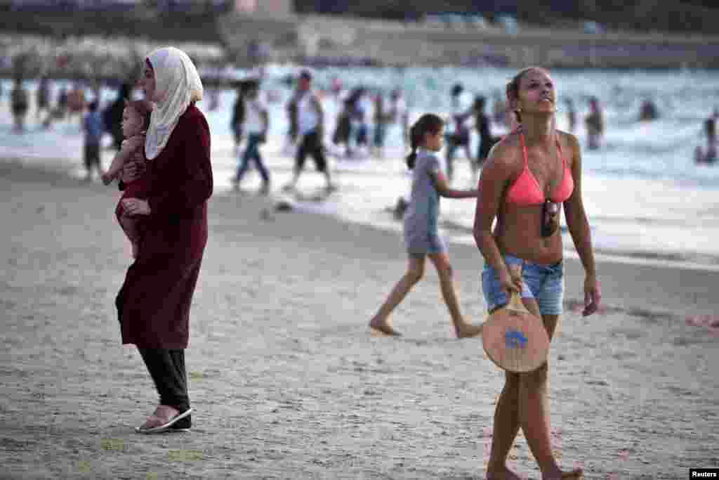 A Palestinian woman (L) holds a baby as she visits a beach in Tel Aviv during Eid al-Fitr, which marks the end of the holy month of Ramadan August 20, 2012.