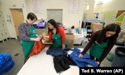In this Friday, Dec. 21, 2018, photo, from left, Rebecca Schaechter, Nicole Herron and Rachel Herron fold and sort donated clothes at Treehouse, a nonprofit organization in Seattle that serves the needs of children in the foster-care system. The charity w