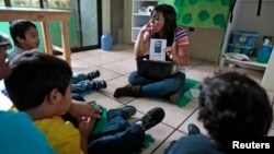 FILE - A teacher talks to children during class at a therapy and development center for autistic kids in Guatemala City.