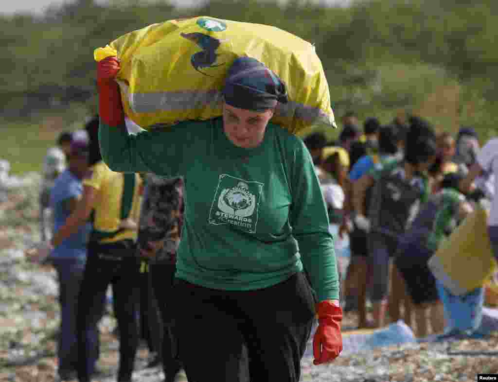 Rebecca Lawson of Pennsylvania, U.S, and a missionary from Stewards of Creation, carries a sack of trash after she joins students, environmental activists and volunteers collecting trash in an effort to clean up the coast of Manila, Philippines.