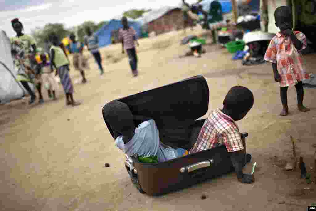 Anak-anak bermain dengan sebuah koper di kamp IDP untuk grup etnik Nuer di kompleks UNMISS di Bor, Sudah Selatan. Ribuan tewas dan hampir sebanyak 900.000 orang dipaksa meninggalkan rumah mereka akibat pertikaian yang telah berlangsung lebih dari dua bulan antara pemberontah dan pasukan pemerintah, yang didukung oleh pasukan dari negara tetangga Uganda.