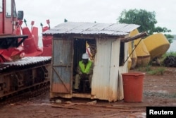 FILE - A worker sits in a hut as it rains at the African Minerals Limited port in Pepel, Sierra Leone.