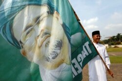 Seorang pemuda muslim memegang bendera bergambar Rizieq Shihab, Jakarta, 2 Desember 2019. (Foto: REUTERS/Willy Kurniawan)