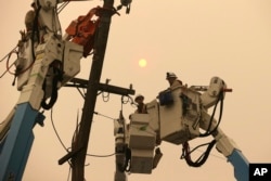 FILE - Pacific Gas & Electric crews work to restore power lines in Paradise, Calif., Nov. 9, 2018.