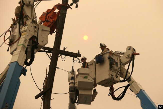 FILE - Pacific Gas & Electric crews work to restore power lines in Paradise, Calif., Nov. 9, 2018.