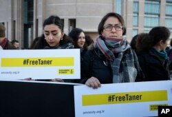 FILE - Human rights activists stage a protest demanding the release of Amnesty International's Taner Kilic, outside a court in Istanbul, Turkey, Jan. 31, 2018.