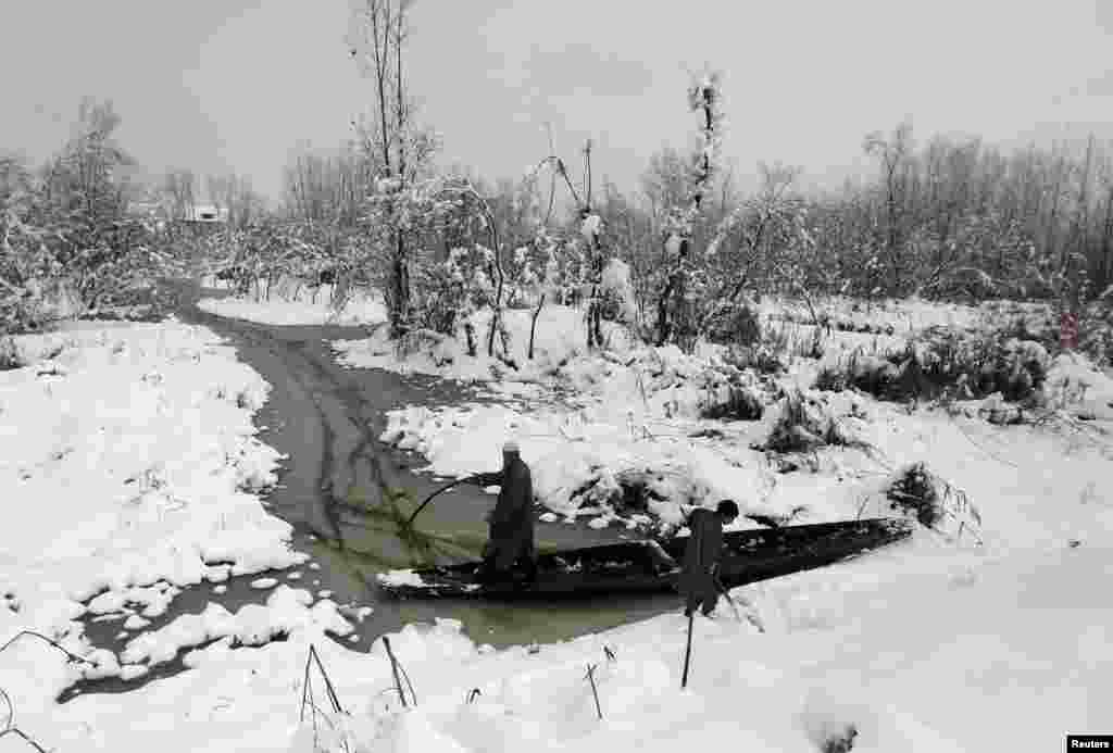 Kashmiri men try to push their boat through the waters of Anchar Lake after heavy snowfall in Srinagar, India.