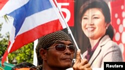 Người biểu tình chống chính phủ phất cờ quốc gia phía trước chân dung của Thủ tướng Thái Lan Yingluck Shinawatra bên ngoài văn phòng của Bộ Giao thông vận tải ở tỉnh Nonthaburi, ngoại ô Bangkok, ngày 29/1/2014.