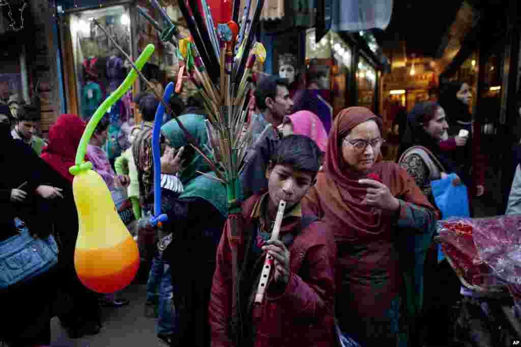 An Indian boy selling balloons plays the flute to attract customers at a busy market ahead of Eid al-Adha in Srinagar, India, October 25, 2012. 