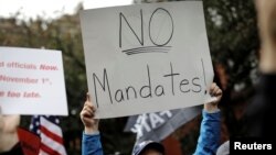 FILE: A demonstrator holds a sign during a protest by New York City Fire Department (FDNY) union members, municipal workers and others, against the city's COVID-19 vaccine mandates in New York City, New York, U.S., Oct. 28, 2021