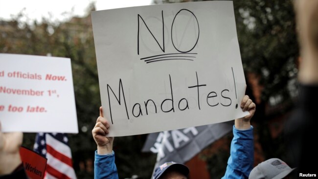 FILE: A demonstrator holds a sign during a protest by New York City Fire Department (FDNY) union members, municipal workers and others, against the city's COVID-19 vaccine mandates in New York City, New York, U.S., Oct. 28, 2021