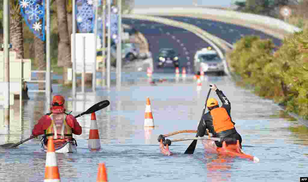 Two men paddle their kayaks through a flooded road in Palavas-les-Flots following overnight storm in southern France, Nov. 23, 2019.