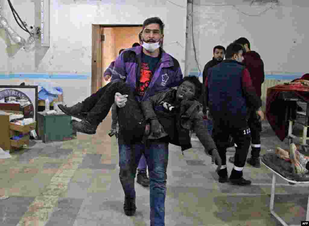 A member of the Syrian Violet Oragnization carries an injured boy at a makeshift hospital following a government airstrike on a vegetable market in Syria's last major opposition bastion of Idlib.