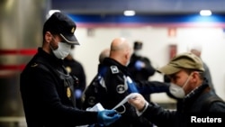 Un policía español reparte tapabocas en una estación del metro de Madrid. El lunes, el gobierno permitió que los trabajarores de construcción y fábricas, regresaran a sus empleos.