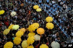 FILE - Protesters holding yellow umbrellas gather to observe a moment of silence to mark the first anniversary of "Umbrella Movement" outside the government headquarters in Hong Kong, Sept. 28, 2015.