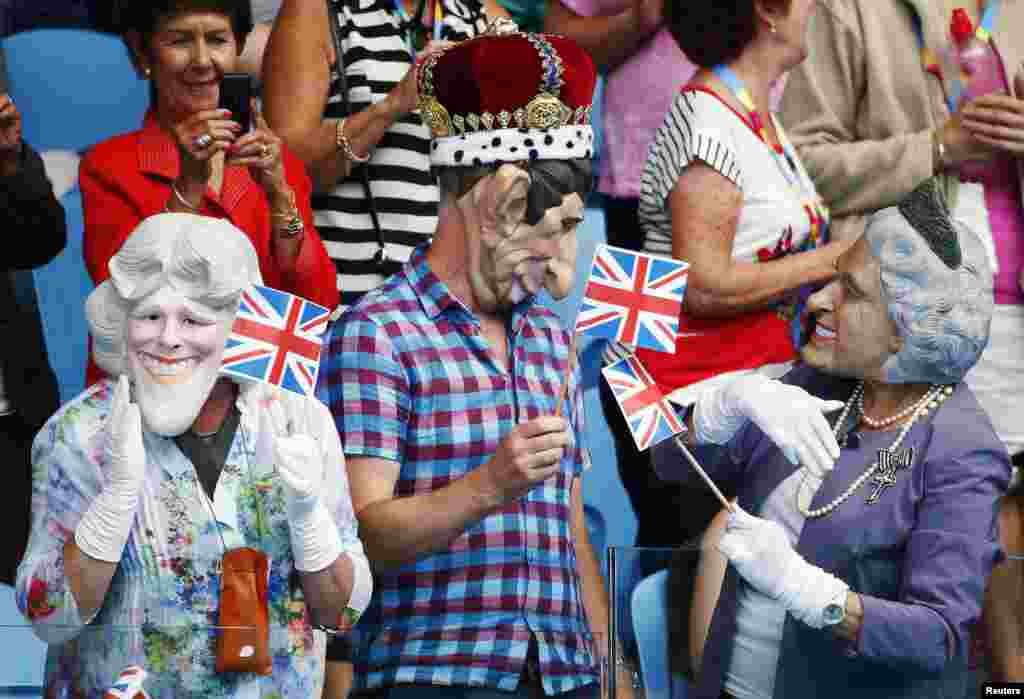 Spectators wearing masks depicting Britain's Royal family hold Union flags during the men's singles first round match between Andy Murray of Britain and Yuki Bhambri of India at the Australian Open 2015 tennis tournament in Melbourne.