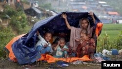 FILE - Rohingya refugees shelter from the rain in a camp in Cox's Bazar, Bangladesh, Sept. 17, 2017.