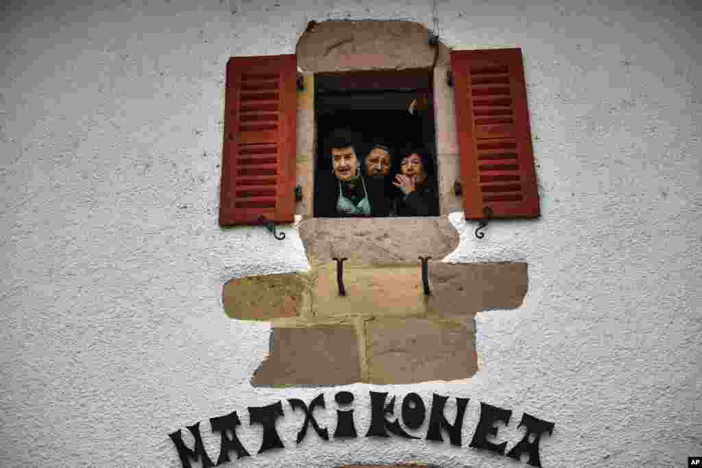 Women look on from the window of a house during the ancient rural carnival in the small Pyrenees village of Lantz, northern Spain.