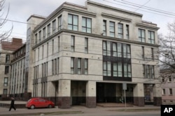 FILE - A women enters the four-story building known as the "troll factory" in St. Petersburg, Russia, April 19, 2015. The “troll factory” is where hundreds of young Russians work around the clock writing blogs and posting comments on the Internet staunchly supporting President Vladimir Putin and attacking the West.