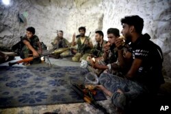 FILE - Fighters with the Free Syrian army eat in a cave where they live, in the outskirts of the northern town of Jisr al-Shughur, Syria, west of the city of Idlib, Sept. 9, 2018.
