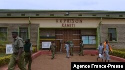 FILE - Kenyan prison warders (L) and prisoners walk past the entrance of the Kamiti Prison, in Nairobi, Feb. 22, 2017.