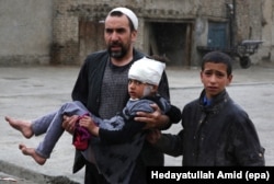 An Afghan man carries a girl who was injured in a suicide bomb blast that targeted the premises of the Ministry of Defense, in Kabul, Afghanistan, 19 April 2016.