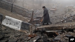 An elderly woman walks across a destroyed bridge toward the airport, the scene of heavy fighting in Donetsk, Ukraine, March 1, 2015. 