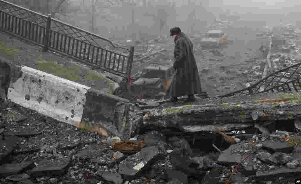 Seorang perempuan tua berjalan di jembatan yang hancur, tempat pertempuran dahsyat di Donetsk, Ukraina, 1 Maret 2015.