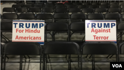 Signs provided by organizers rest on chairs in the hall ahead of Donald Trump's speech to Hindu Americans. (E. Sarai/VOA)